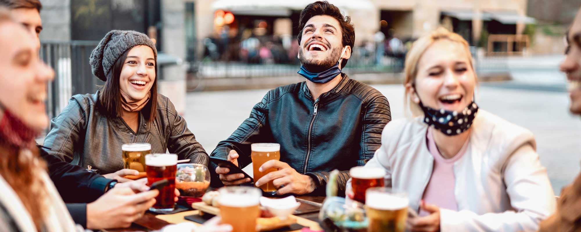 Young people sat around a pub table drinking beer