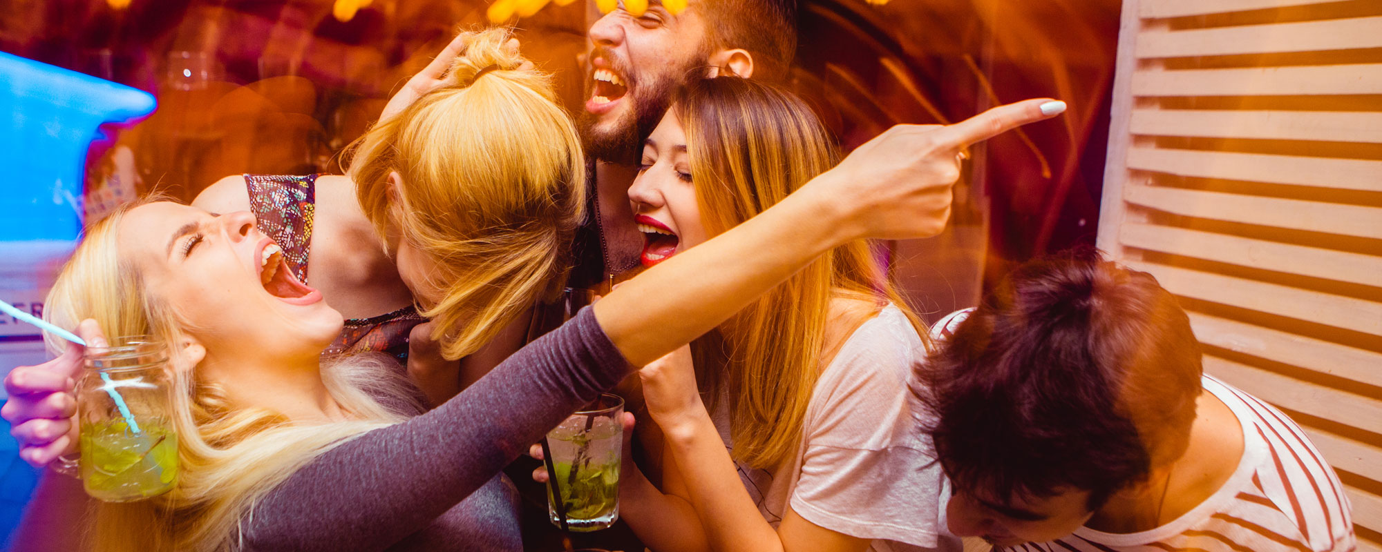 Young people laughing and drinking at a club